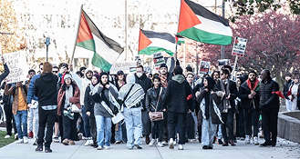Young people marching with Palestinian flags at a campus protest