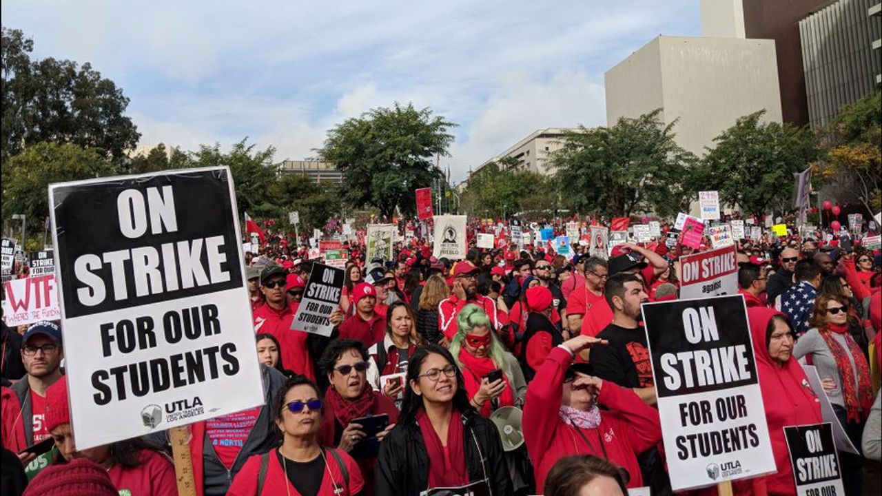 UTLA teachers on strike wearing red shirts holding ON STRIKE FOR OUR STUDENTS signs